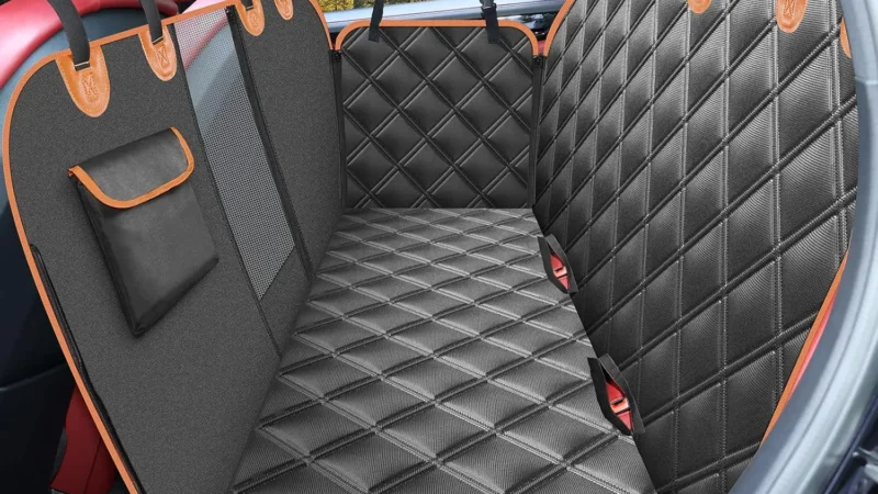 Housse de siège auto KYG noire à liseré orange installée sur la banquette arrière d'une voiture